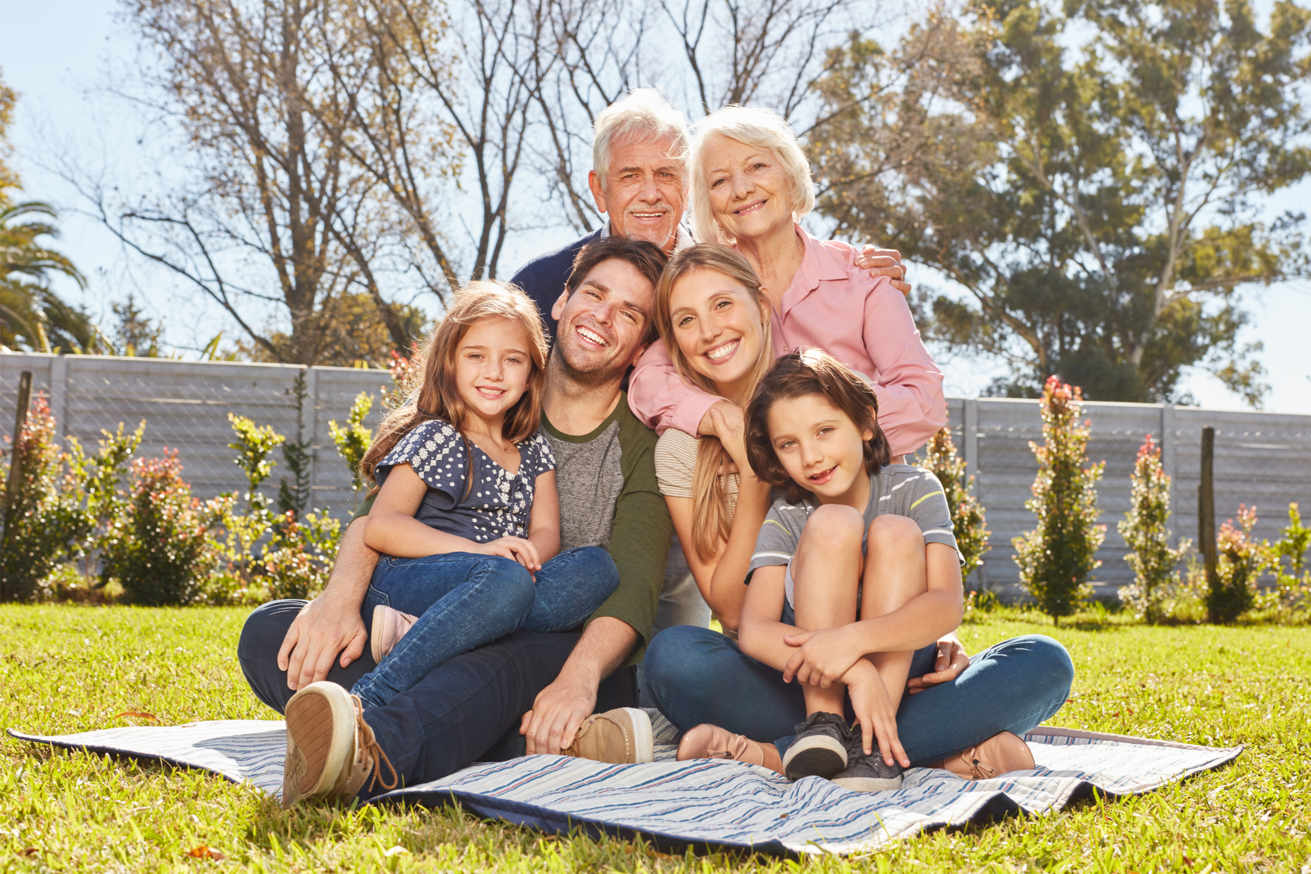 Multi-generational family outside on a blanket smiling.