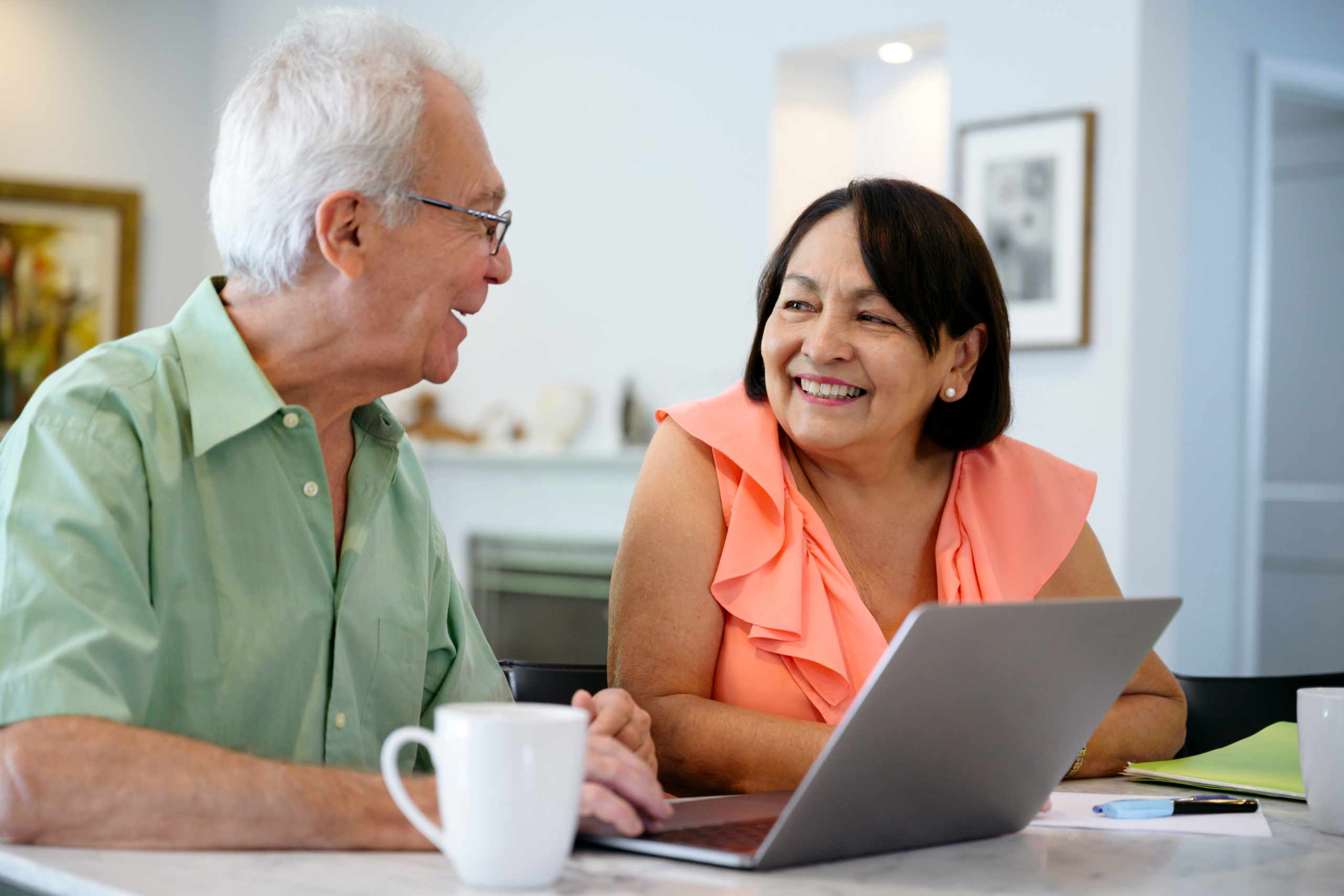 Older couple at table drinking coffee with computer